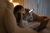 Женщина разговаривает по мобильному телефону в спальне дома — стоковое фото