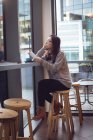 Продумана жінка тримає журнал, маючи каву в кафетерії — стокове фото