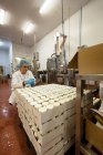 Женщина-работница упаковывает бутылки на пищевой фабрике — стоковое фото