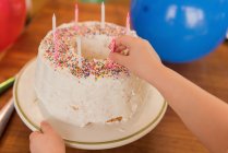 Gros plan de fille mettant bougie sur gâteau d'anniversaire — Photo de stock