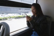 Teenage girl using mobile phone in the bus — Stock Photo