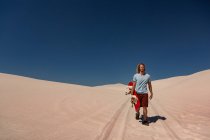 Man with sandboard walking in the desert on a sunny day — Stock Photo
