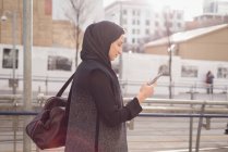 Жінка в хіджабі, використовуючи мобільний телефон в сонячний день — стокове фото