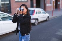 Teenage girl taking photo with camera in city street — Stock Photo