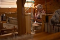 Активна старша жінка, що плете шовк в магазині — стокове фото