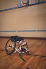 Пустое инвалидное кресло и баскетбольный мяч на корте — стоковое фото