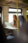 Червоне волосся молода жінка використовує свій ноутбук у потязі — стокове фото