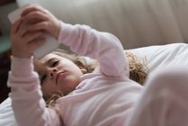 Bambina che utilizza il telefono cellulare in camera da letto a casa — Foto stock
