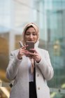 Жінка в хіджабі, використовуючи мобільний телефон на міській вулиці — стокове фото