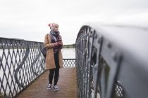 Nachdenkliche Frau hört Musik mit Kopfhörer auf Brücke — Stockfoto