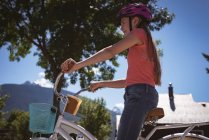 Smiling girl in helmet riding bicycle in country. — Stock Photo