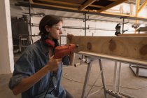 Female artisan using drilling machine in workshop. — Stock Photo