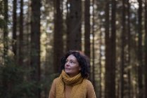 Задумчивая женщина-туристка стоит в лесу — стоковое фото