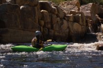 Mujer kayak en río por rocas a la luz del sol . - foto de stock