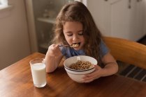 Fille petit déjeuner céréales et lait sur la table à la maison — Photo de stock