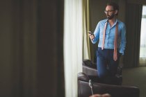 Бізнесмен, використовуючи мобільний телефон в готельному номері — стокове фото