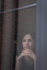 Femme cadre regardant par la fenêtre dans le bureau — Photo de stock
