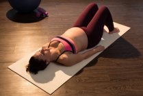 Mulher grávida realizando ioga na sala de estar — Fotografia de Stock