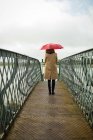 Rückansicht einer Frau, die mit Regenschirm am Bahnhof steht — Stockfoto