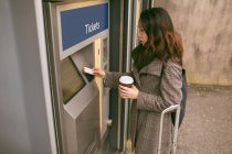 Frau nimmt Fahrkarte am Bahnsteig aus Automat — Stockfoto