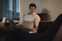 Homem de negócios verificando documentos ao usar tablet digital no quarto — Fotografia de Stock