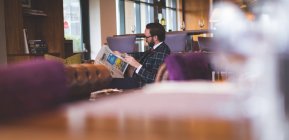 Бизнесмен читает газеты, выпивая виски в отеле — стоковое фото