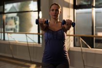 Беременная женщина упражняется с гантелями дома — стоковое фото
