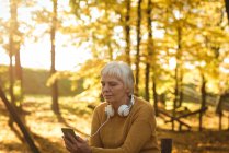 Seniorin an sonnigem Tag mit Handy im Park — Stockfoto