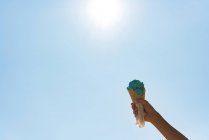 Mano de niño sosteniendo helado contra el cielo en un día soleado - foto de stock