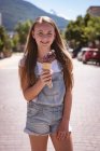 Front view of girl with ice cream standing on road in town. — Stock Photo