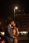 Casal romântico beijando uns aos outros na estrada à noite — Fotografia de Stock