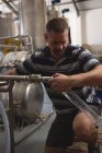 Чоловічий працівник, що заповнює джин у вимірювальному циліндрі від винокурні на заводі — стокове фото