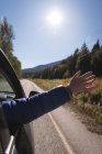 Woman waving her hand out of car window while travelling — Stock Photo