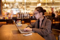 Female executive using laptop at table in hotel — Stock Photo