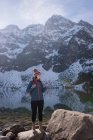 Escursionista femminile utilizzando il telefono cellulare sul lungolago durante l'inverno — Foto stock