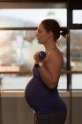 Femme enceinte exerçant avec haltère à la maison — Photo de stock