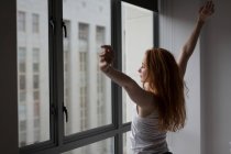 Young woman standing with arms outstretched at home — Stock Photo