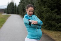 Mulher grávida usando telefone celular no parque — Fotografia de Stock