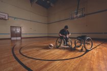 Disabled man adjusting belt of wheelchair in the court — Stock Photo