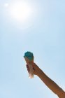 Mão de criança segurando sorvete contra o céu em um dia ensolarado — Fotografia de Stock