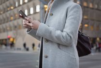 Mid section of woman using mobile phone at railway station — Stock Photo