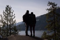 Rear view of hiker couple standing on rock near riverside on a sunny day — Stock Photo