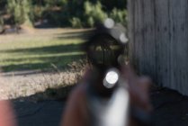 Homem desfocado apontando rifle sniper no alvo no alcance de tiro em um dia ensolarado — Fotografia de Stock