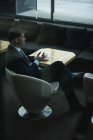 Удумливий бізнесмен використовує мобільний телефон, маючи каву в готельному лобі — стокове фото