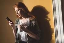 Женщина, пользующаяся мобильным телефоном, пьет кофе дома — стоковое фото