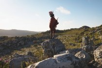 Задумчивый человек масаи, стоящий с палкой на камне — стоковое фото