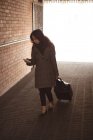 Жінка використовує мобільний телефон під час прогулянки на залізничній станції — стокове фото