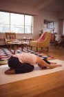 Femme effectuant du yoga dans le salon à la maison — Photo de stock
