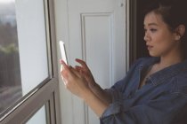 Mujer tomando fotos con teléfono móvil en casa - foto de stock