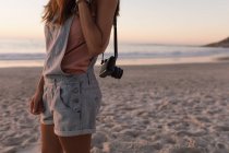 Mid section of woman with vintage camera in sandy beach at dusk — Stock Photo